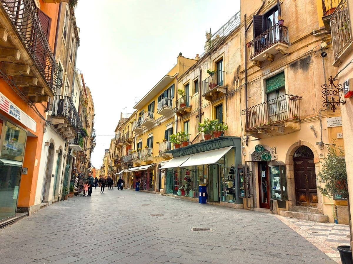 The charming streets of Taormina's old town, with its colorful buildings adorned with balconies and greenery, showcase vibrant street life and traditional Sicilian architecture, inviting exploration and discovery.