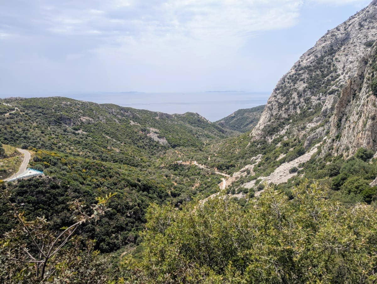 Von einer hohen Aussichtsstelle blickt man über grüne Hügel und Schluchten bis hin zum blauen Meer am Horizont. Dieser Ausblick bietet sich kurz vor oder direkt bei der Höhle des Pythagoras und belohnt den anstrengenden Aufstieg.