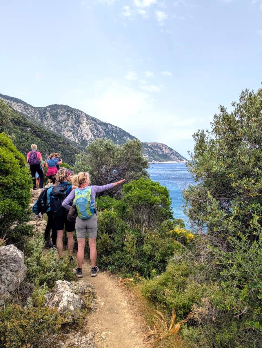 Küstenwanderung auf schmalem Pfad entlang steiler Hänge mit Blick auf das türkisfarbene Meer – ein Highlight beim Urlaub auf Samos mit Froschreisen. Die Wandergruppe genießt die Aussicht auf die dramatische Felsküste und das offene Wasser.